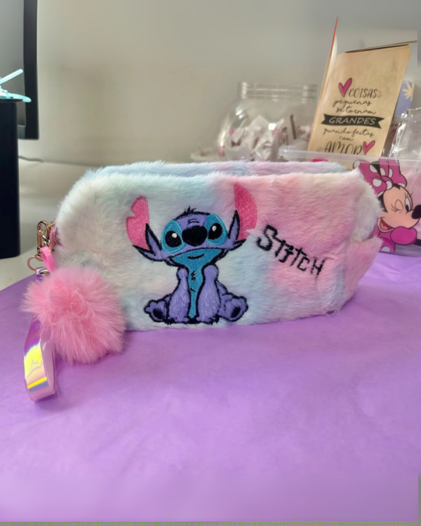 Necessaire felpuda multicolorida do Stitch com bordado frontal e pom-pom rosa no zíper.